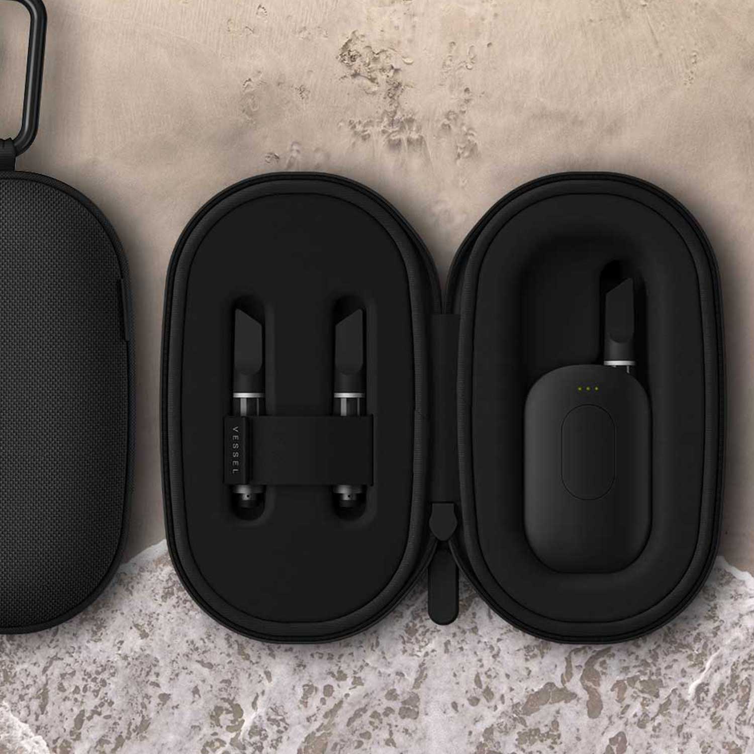 Two black Vessel Scout cases on concrete surface: closed case on left, open case on right displaying matte black Compass battery and two cartridges